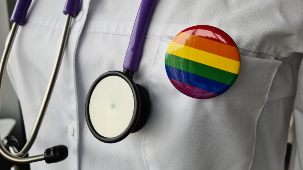 A doctor wearing a stethoscope and a LGBTQ+ badge